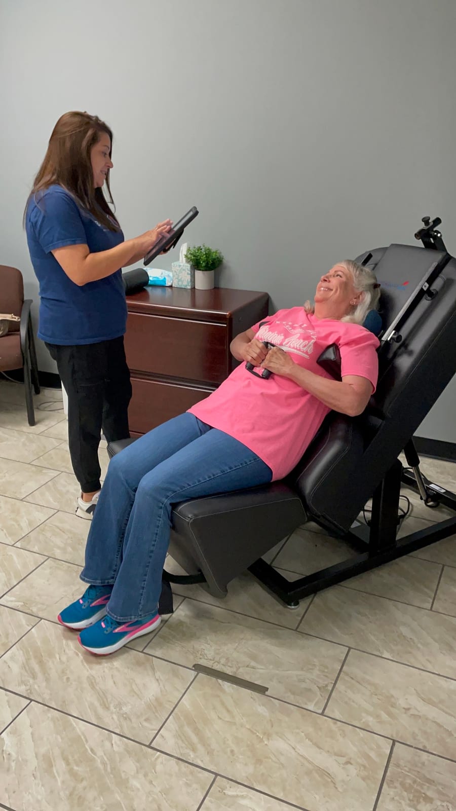 A patient seated and reclined during a treatment visit, talking with a clinic team member